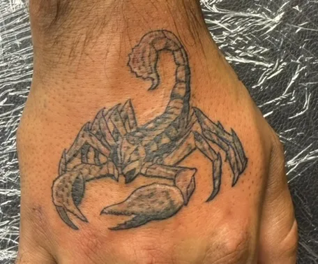 Black and gray scorpion tattoo on hand
